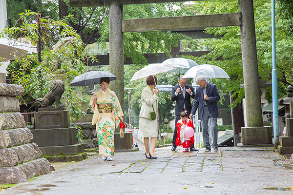 東京都新宿区の諏訪神社で傘を差して歩く七五三記念日の家族